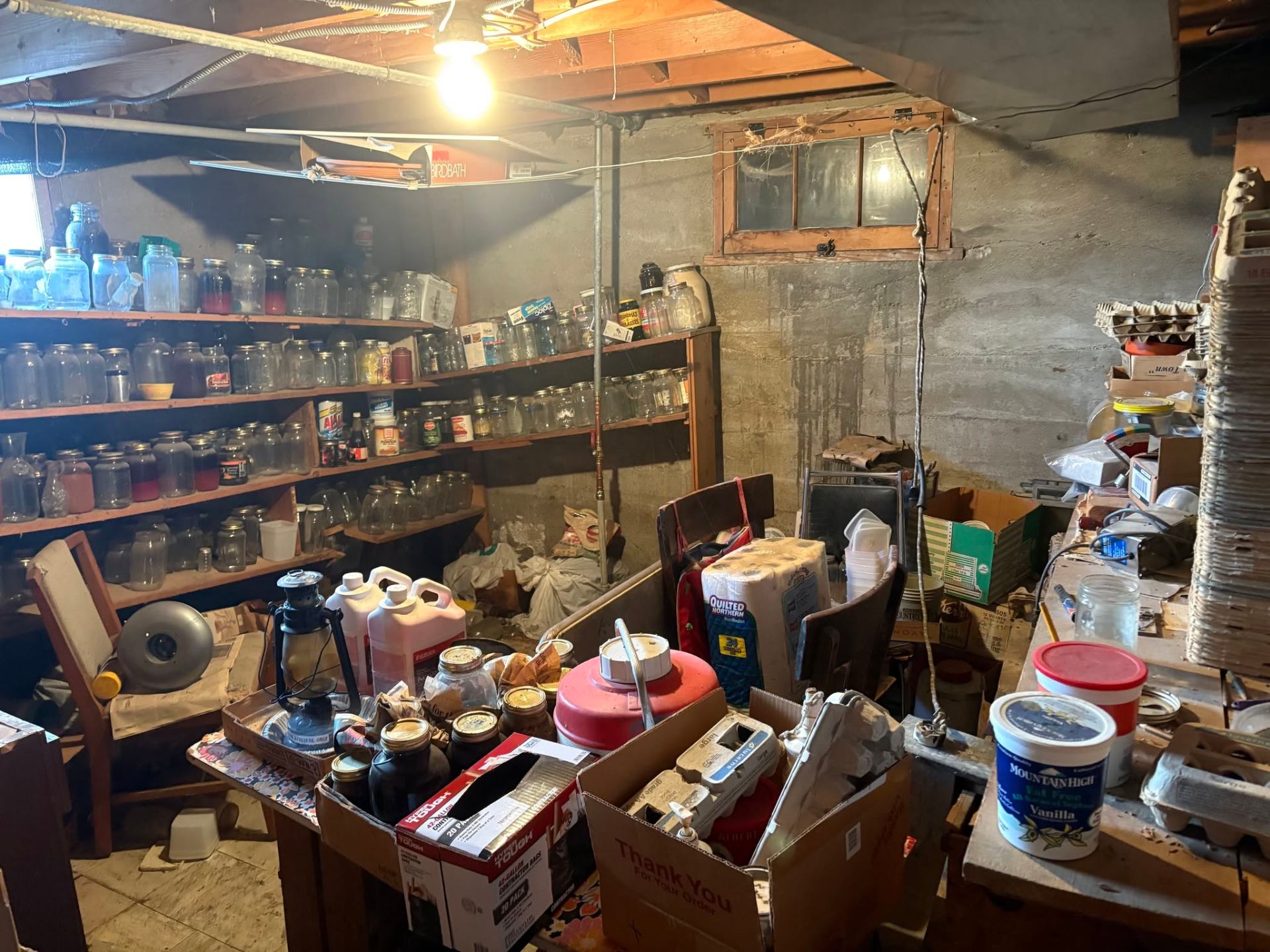 Cluttered Maryland basement filled with jars, boxes, furniture and household items before cleanout